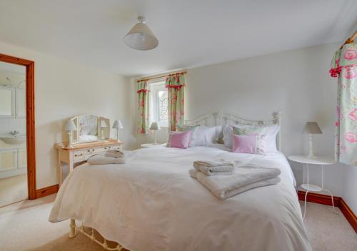 a bedroom with a large white bed with towels on it at Finder's Cottage in Docking