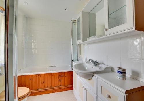 a bathroom with a sink and a mirror and a tub at Finder's Cottage in Docking