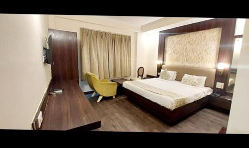 Habitación de hotel con cama y silla amarilla en FabHotel Prime Garden View en Jaipur