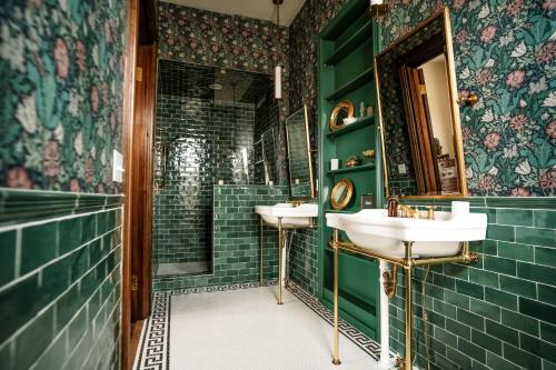 baño con 2 lavabos y paredes de azulejos verdes en Henrie House I Luxury 4BR Downtown Historic Gem with Library & Patio, en Nashville