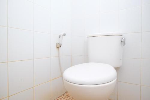 a white toilet in a white tiled bathroom at RedDoorz Syariah at Griya Hanum Condoongcatur in Kejayan