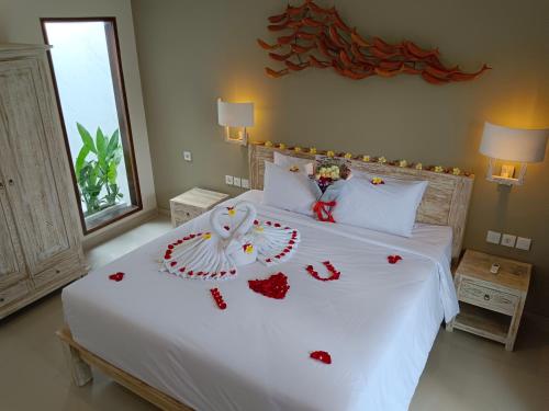 Un dormitorio con una cama blanca con corazones rojos. en Kubu Garden Suites & Villas Nusa Dua, en Nusa Dua