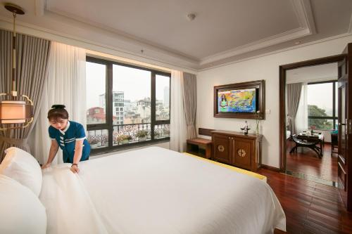 San Grand Hotel & Spa في هانوي: فتاة صغيرة تقف على سرير في غرفة فندق