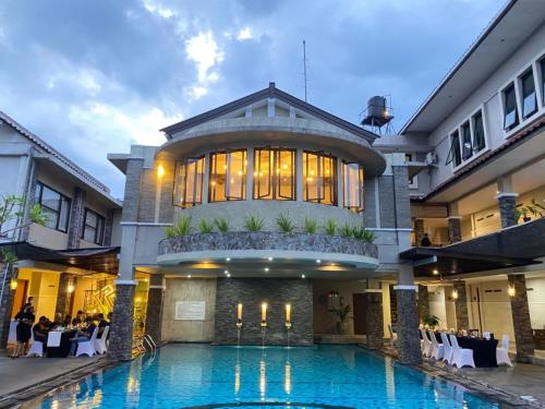 a hotel with a swimming pool in front of a building at Hotel Sriti Magelang in Magelang