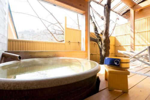 a large bath tub in a room with a large window at Shosenkaku in Nagano