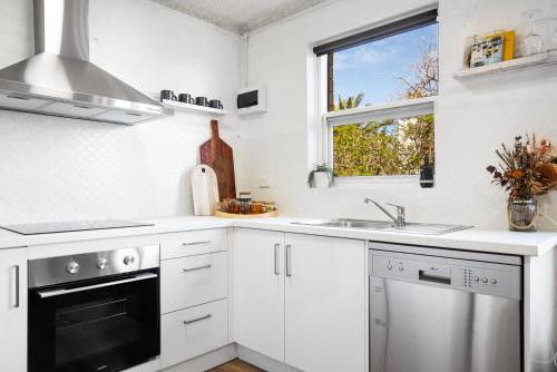 a kitchen with white cabinets and a sink and a window at Ray's Place by the Riverside in Glenelg