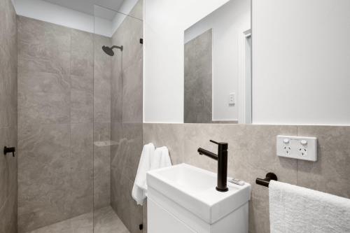 een badkamer met een witte wastafel en een douche bij Lemon & Salt Studio Glenelg South in Glenelg