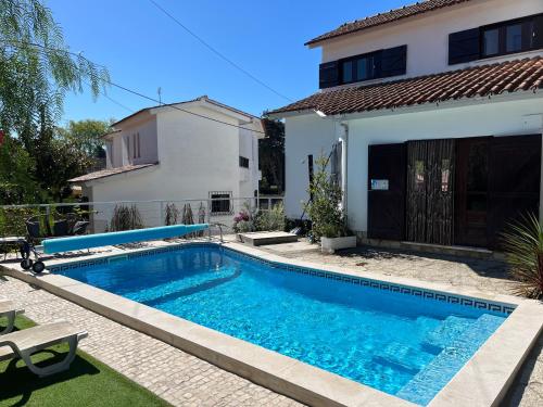 a swimming pool in front of a house at Casa Pausa Sesimbra Holiday Home in Sesimbra
