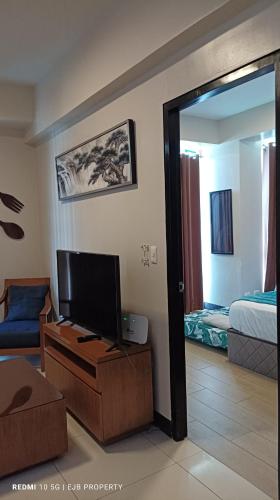 a living room with a television and a bedroom at Mactan Newtown Beach Condo in Mactan