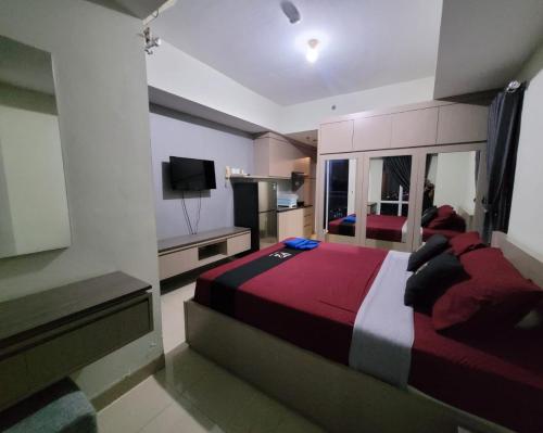 een slaapkamer met een groot bed en een televisie bij Apartemen grand dhika city by PLANET ZONA in Padurenan
