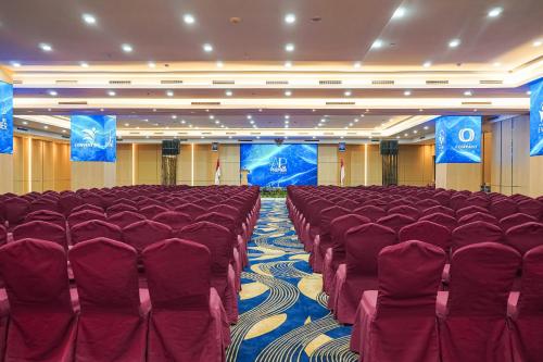 a conference room with red chairs and a stage at AP Premier Batam in Nagoya