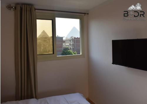 a bedroom with a window and a flat screen tv at Badr pyramids inn in Cairo