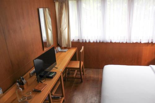 a bedroom with a bed and a desk with a television at Natuna Dive Resort in Ranai