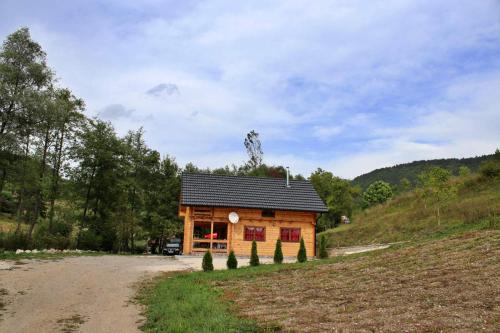 una cabaña de madera en un campo junto a un camino de tierra en Eko kuca Jandro, en Šipovo