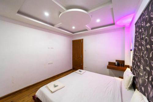 a bedroom with a white bed with purple lighting at Fortune Retreats in Ooty