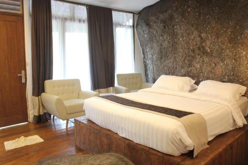 a bedroom with a large bed with a stone wall at Natuna Dive Resort in Ranai