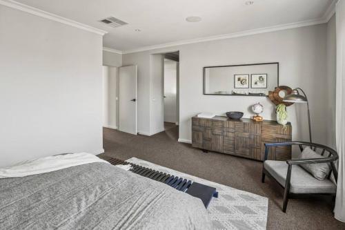 a bedroom with a bed and a chair at Werribee Gem Luxe Home Family Getaway 6Bed Netflix in Werribee