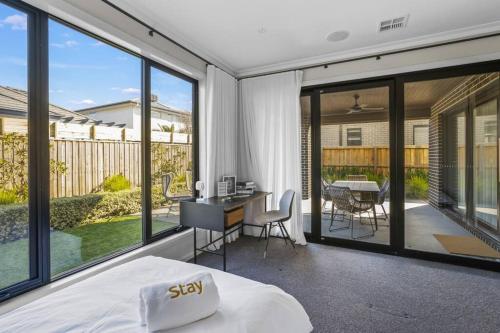 a bedroom with a bed and a balcony with a table at Werribee Gem Luxe Home Family Getaway 6Bed Netflix in Werribee