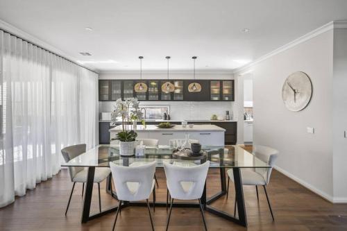 a dining room with a glass table and white chairs at Werribee Gem Luxe Home Family Getaway 6Bed Netflix in Werribee