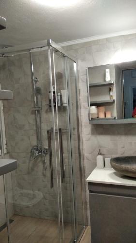 a bathroom with a glass shower with a sink at Beach Retreat in town in Korinthos