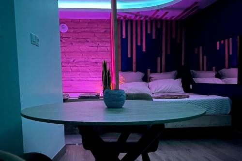 Zimmer mit einem Tisch und einem Bett mit violetten Lichtern in der Unterkunft Zen Room in LʼIsle-sur-le-Doubs