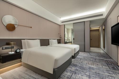 a hotel room with two beds and a flat screen tv at Crowne Plaza Jiangmen Binjiang by IHG in Jiangmen
