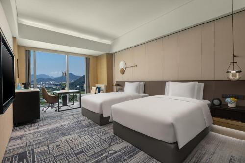 ein Hotelzimmer mit 2 Betten und einem TV in der Unterkunft Crowne Plaza Jiangmen Binjiang, an IHG Hotel in Jiangmen