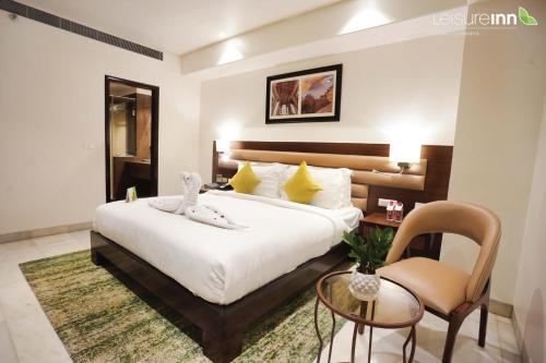 a bedroom with a bed and a table and a chair at Leisure Inn Grand Chanakya in Jaipur