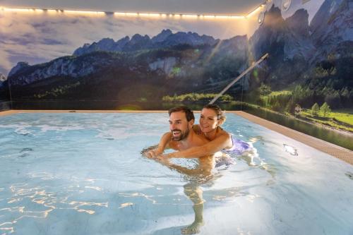 a man and a woman in a bathtub in a mountain pool at Wellness- und Familienoase Dachsteinresort in Russbach am Pass Gschütt