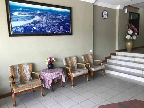 a waiting room with chairs and a table and a picture at Theatreinn Sri Aman in Sri Aman
