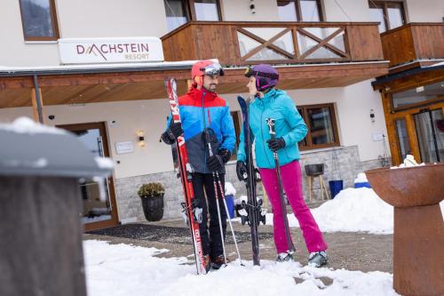 two people are standing in the snow with skis at Wellness- und Familienoase Dachsteinresort in Russbach am Pass Gschütt