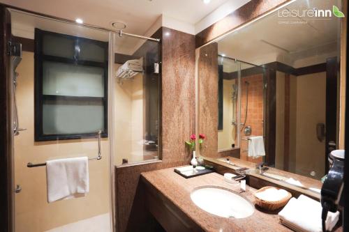 a bathroom with a sink and a large mirror at Leisure Inn Grand Chanakya in Jaipur