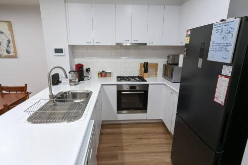 a kitchen with white cabinets and a black refrigerator at 3 bedroom condo opposite casino. in Melbourne