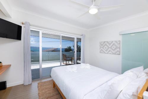 een slaapkamer met een wit bed en een groot raam bij Serendipity in Forster
