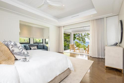um quarto com uma cama branca e vista para o oceano em One Beachlands - Luxury Beachfront Mansion em Saint James