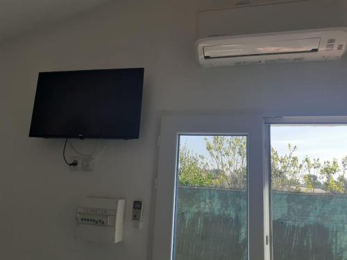 Une télévision à écran plat est installée sur un mur à côté d'une fenêtre. dans l'établissement Studio- Terrasse -Place de parking privé, à Marseille