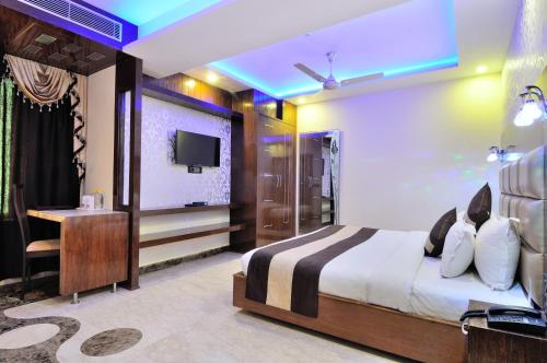 a bedroom with a bed and a desk and a television at Crystal Ganga Heights 5 Min from Har Ki Pauri in Haridwār