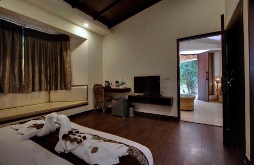una camera da letto con un letto, una scrivania e uno specchio di Corbett Tusker Trail a Kāshīpur
