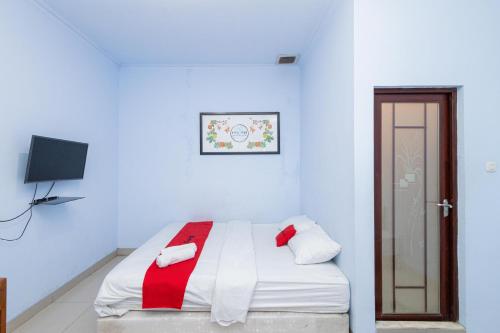 a white room with a bed with red and white sheets at RedDoorz near Wisata Museum Angkut 3 in Batu
