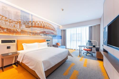 1 dormitorio con 1 cama, escritorio y TV en Hampton by Hilton Wuhan High-Speed Railway Station en Qingshan