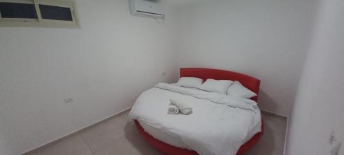 uma pequena cama num quarto com uma cadeira vermelha em לב במדבר - הצימר של רחלי em Arad