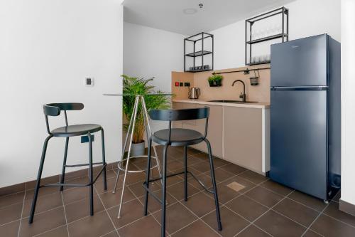 a kitchen with two bar stools and a refrigerator at Emirates Sports Hotel, Dubai Sports City in Dubai