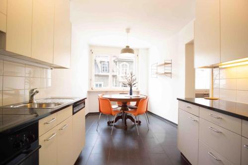 uma cozinha com uma mesa e cadeiras cor de laranja em Modern 3-bedroom apartment in city centre em Basileia