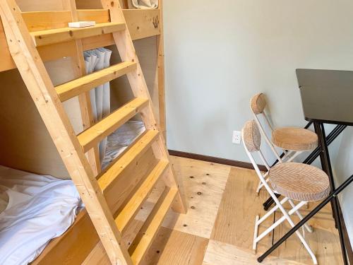 uma cama alta num quarto com uma secretária e cadeiras em YUKARA LEAF LODGE em Nanae