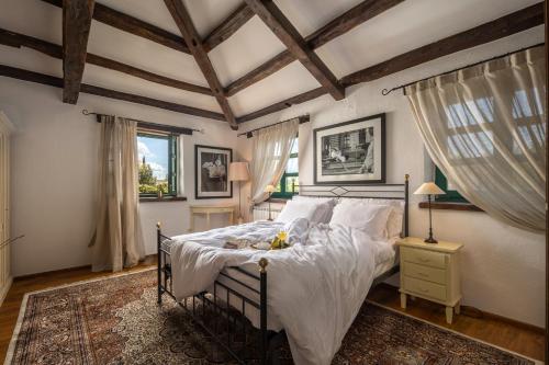 a bedroom with a bed with white sheets and wooden ceilings at Villas Orbani by Istarski Dvori in Sveti Lovreč Pazenatički