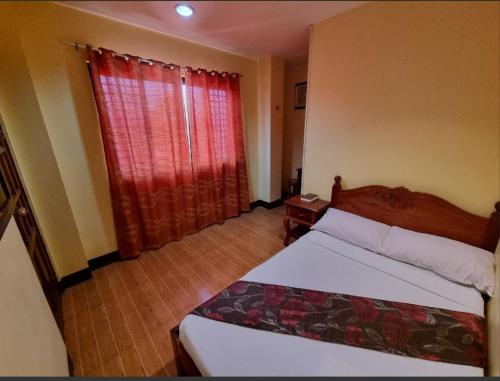 een slaapkamer met een bed en een raam met rode gordijnen bij Mojica Residencia in Vigan