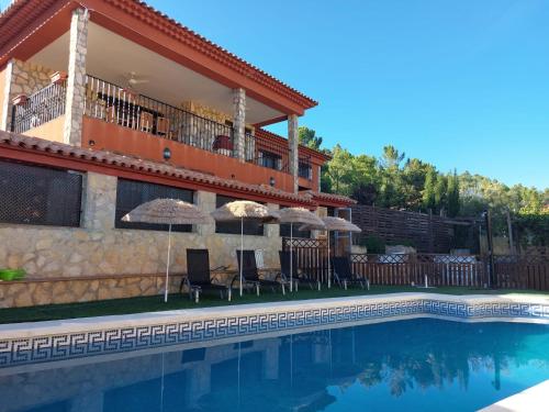 a house with a swimming pool with chairs and umbrellas at La Atalaya de Villalba in Cuenca