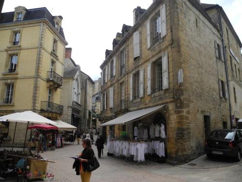 a woman walking down a city street with a store at Escapade cosy au coeur de la cité médiévale in Sarlat-la-Canéda