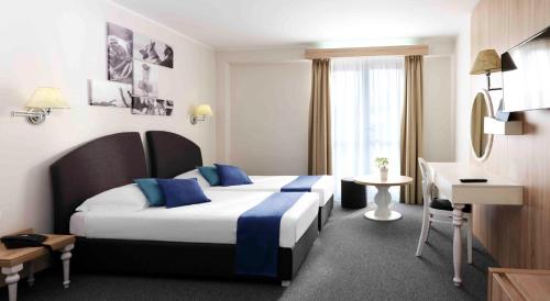 una camera d'albergo con 2 letti e una scrivania di Hotel Mirna - Terme & Wellness Lifeclass a Portoroz
