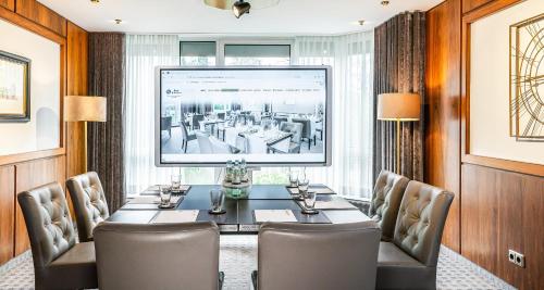 a conference room with a table and chairs and a large screen at Best Western Victor's Residenz-Hotel Rodenhof in Saarbrücken
